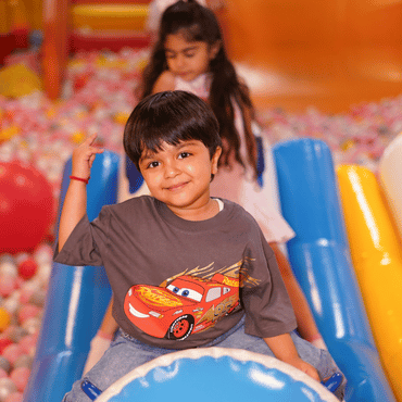 Child enjoying a slide in the colourful ball pit at Wooray Delhi indoor play area.