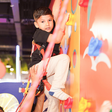 Child climbing an indoor rock climbing wall at Wooray Delhi play area.