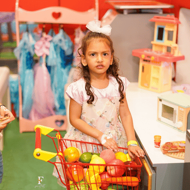 Child enjoying pretend shopping with a toy shopping cart at Wooray Delhi indoor play area.