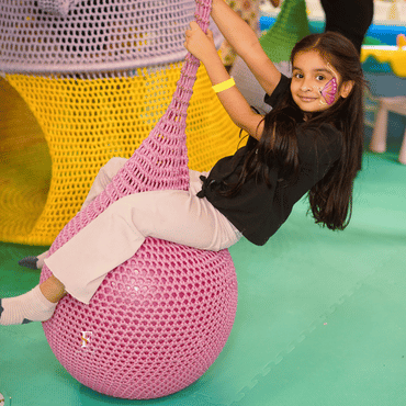 Child enjoying a colourful net swing activity at Wooray Delhi indoor play area.