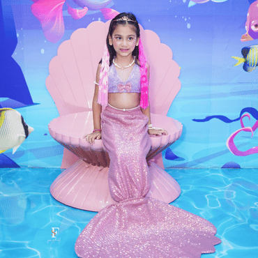 Child dressed as a mermaid sitting on a shell in a colourful underwater-themed setting at Wooray Delhi.