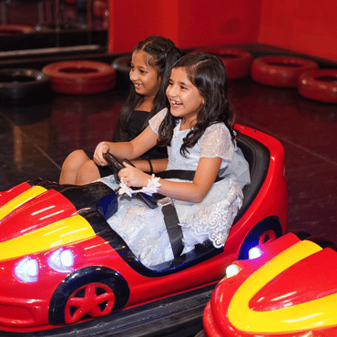 Two children enjoying a fun bumper car ride at Wooray Delhi indoor play area.