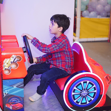 Child enjoying a car racing game at Wooray Delhi indoor play area.